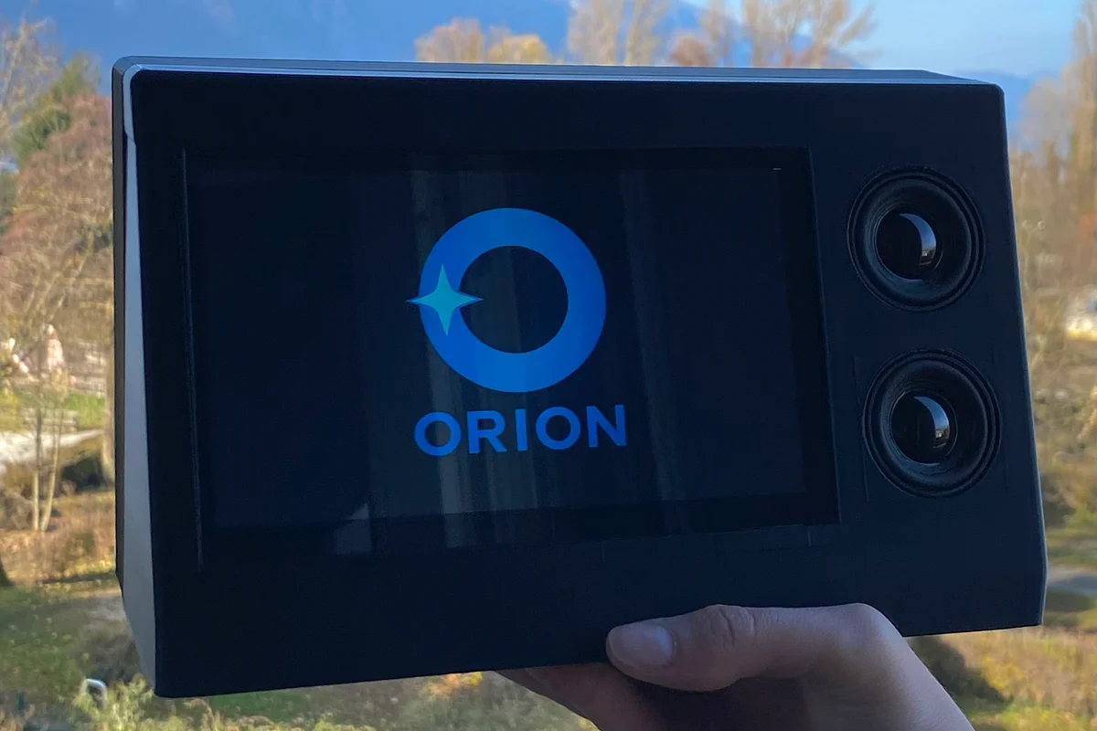 Le terminal Orion tenu à la main en extérieur, son logo affiché à l’écran